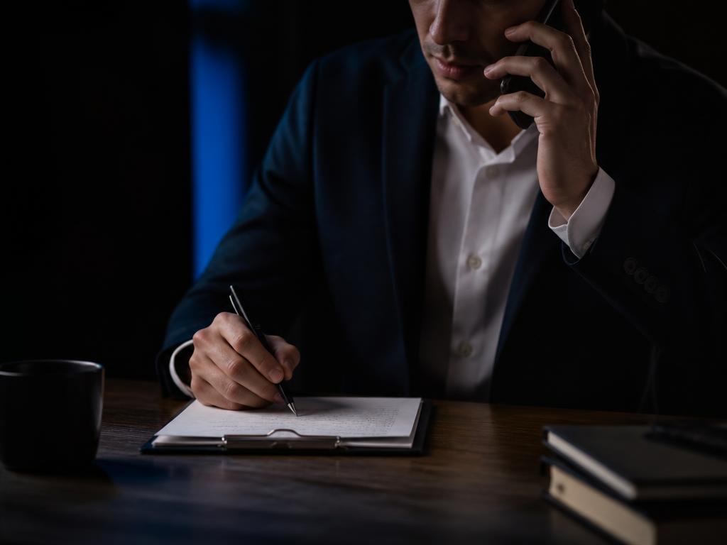 Sales rep on a phone call taking notes on a clipboard while qualifying a lead
